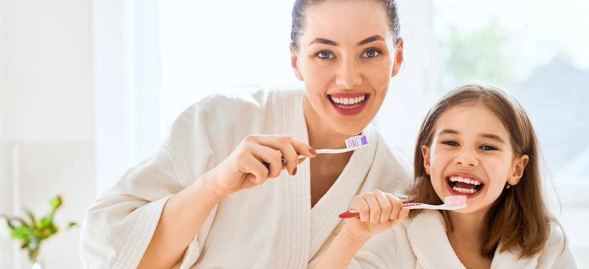 Mamá cuidando la salud oral de su hija