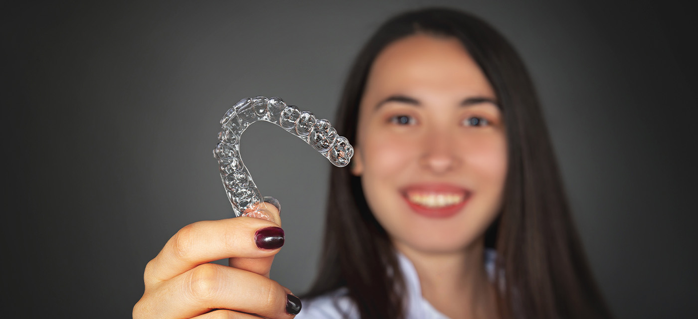 Mujer mostrando que tiene tratamiento con ortodoncia invisible 