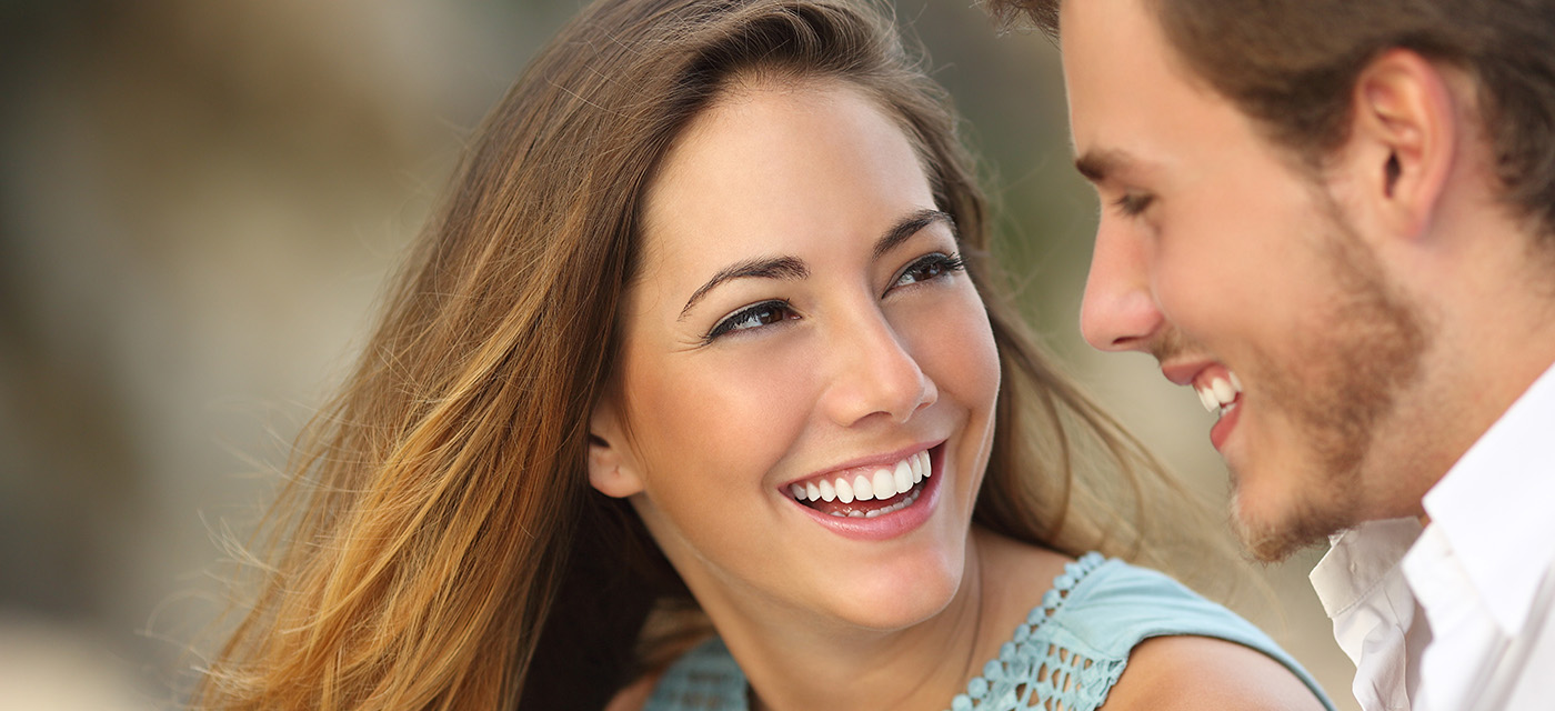 Mujer y hombre sonríen viéndose a los ojos